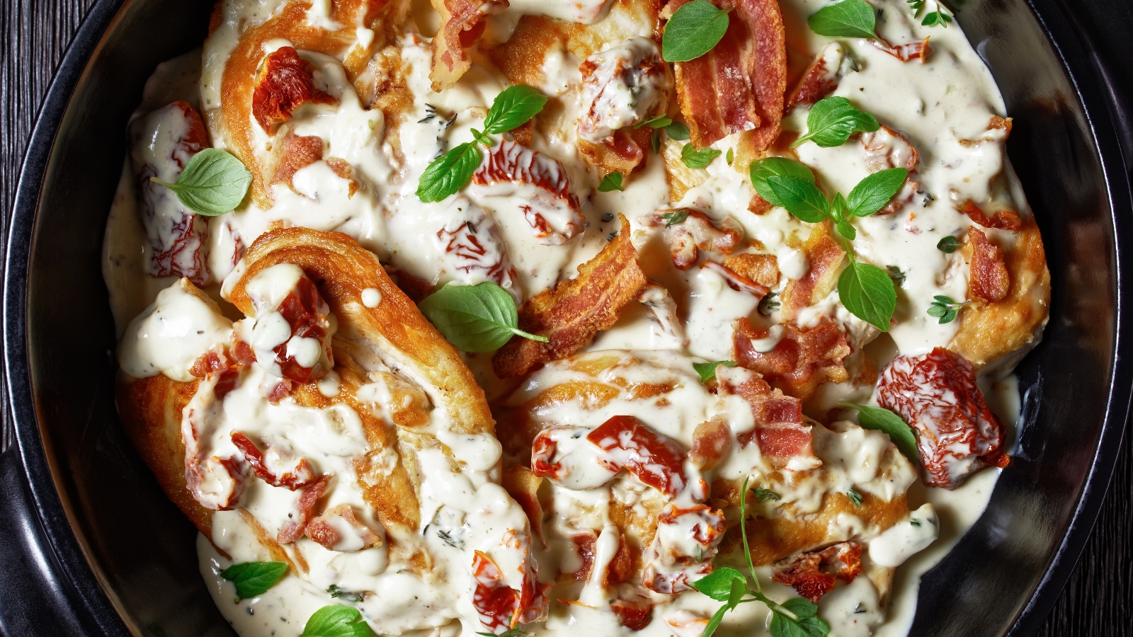 Chicken in cream sauce topped with bacon, tomatoes, and fresh herbs.