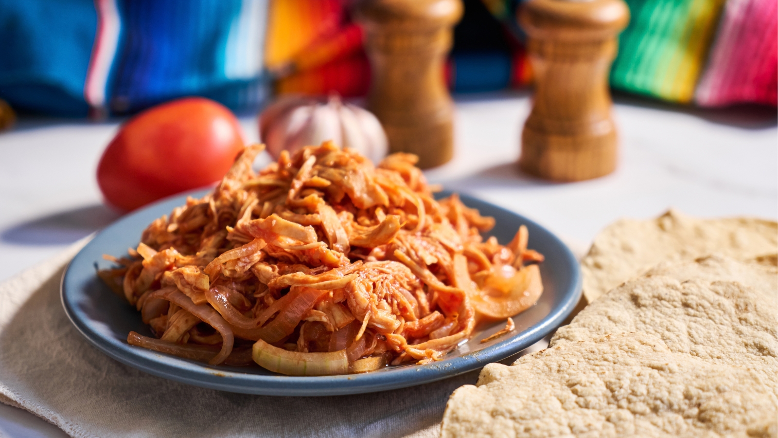 Shredded chicken in tomato sauce served beside tortillas.