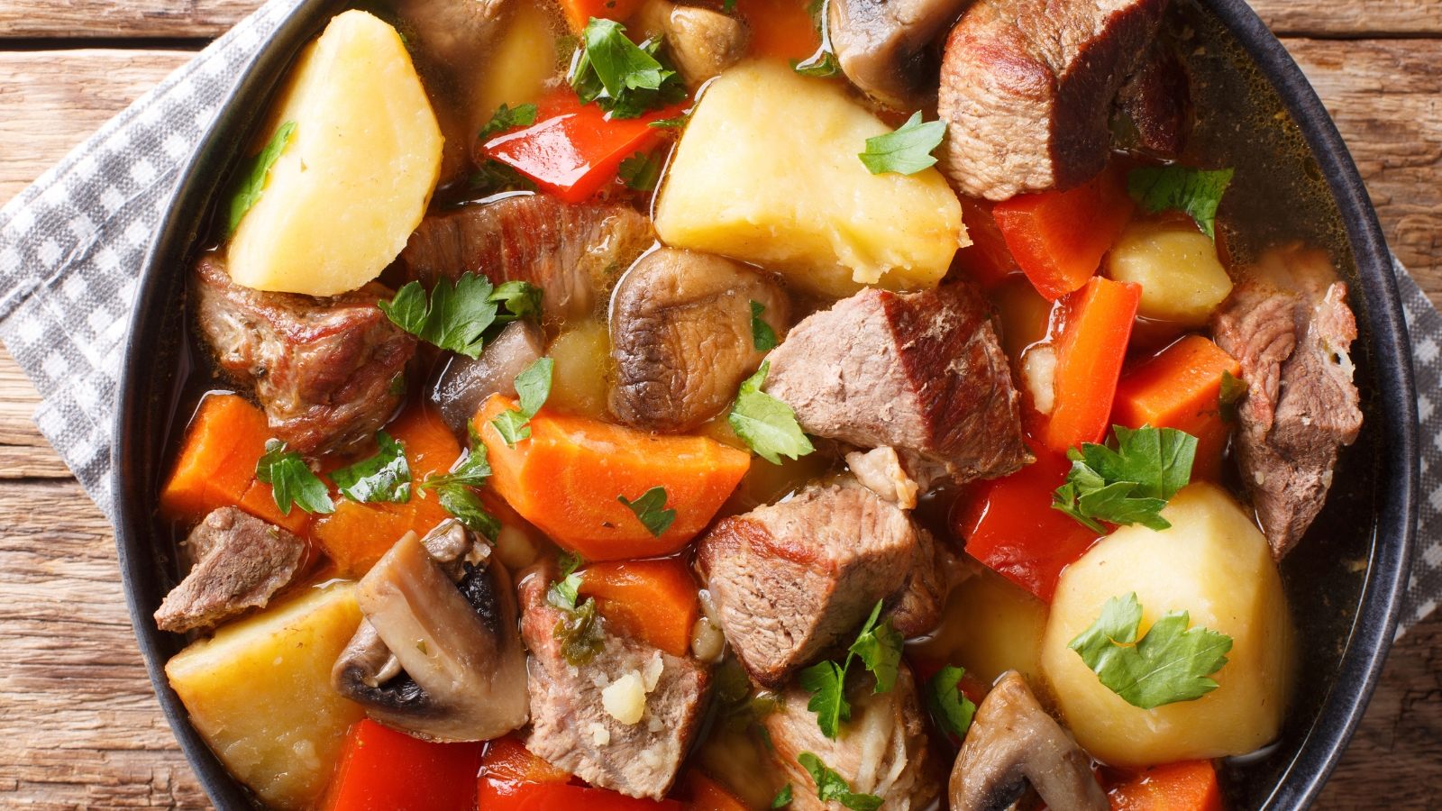 Beef stew with golden potatoes, carrots, mushrooms, and peppers.