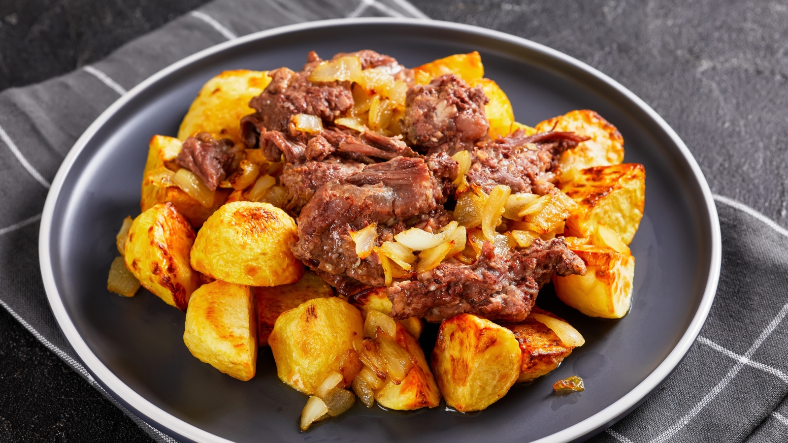 Beef pot roast served over golden potatoes with onions.