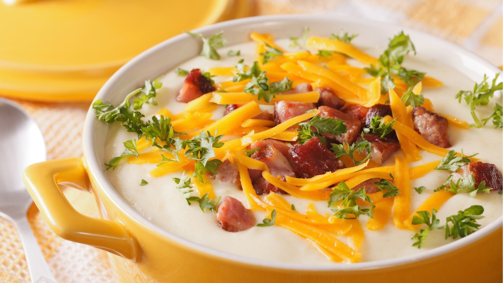 Creamy potato soup topped with bacon, shredded cheddar, and herbs.